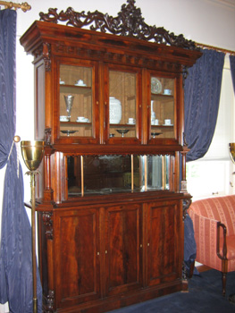An imposing mahogany wood breakfront /display cabinet circa 1870 in a heavy Rococo style.