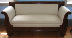 Empire settee with ivory upholstery; mahogany and veneered wood, straight top, curved arms, circa 1860.